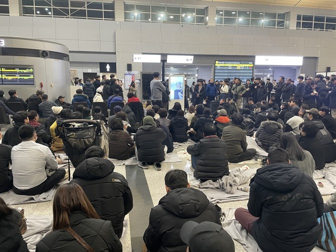 지난 29일 무안국제공항에 모인 유가족들이 한 유가족의 호소를 바라보고 있다. 이 유가족은 즉시 소통할 수 있는 현장소통실 설치를 요구했다. =강경식 기자