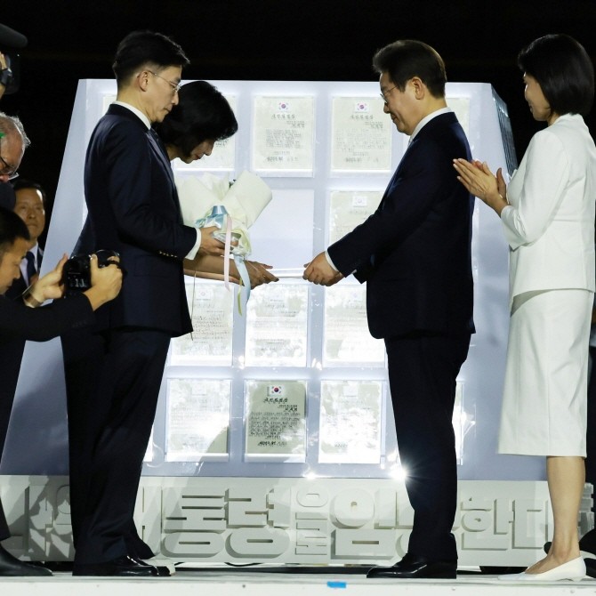 이재명 대통령이 15일 서울 세종대로 광화문광장에서 열린 제21대 대통령 국민임명식 '광복 80년, 국민주권으로 미래를 세우다' 행사에서 이국종 국군대전병원장 등으로부터 빛의 임명장을 받고 있다. ⓒ 연합뉴스