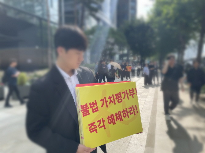 29일 한국감정평가사협회가 서울 여의도 여의도동 일원 KB국민은행 신관 앞에서 '국민은행의 감정평가시장 불법 침탈행위 규탄대회'를 개최했다. 사진은 협회 한 관계자가 피켓을 들고 있는 모습. = 박선린 기자